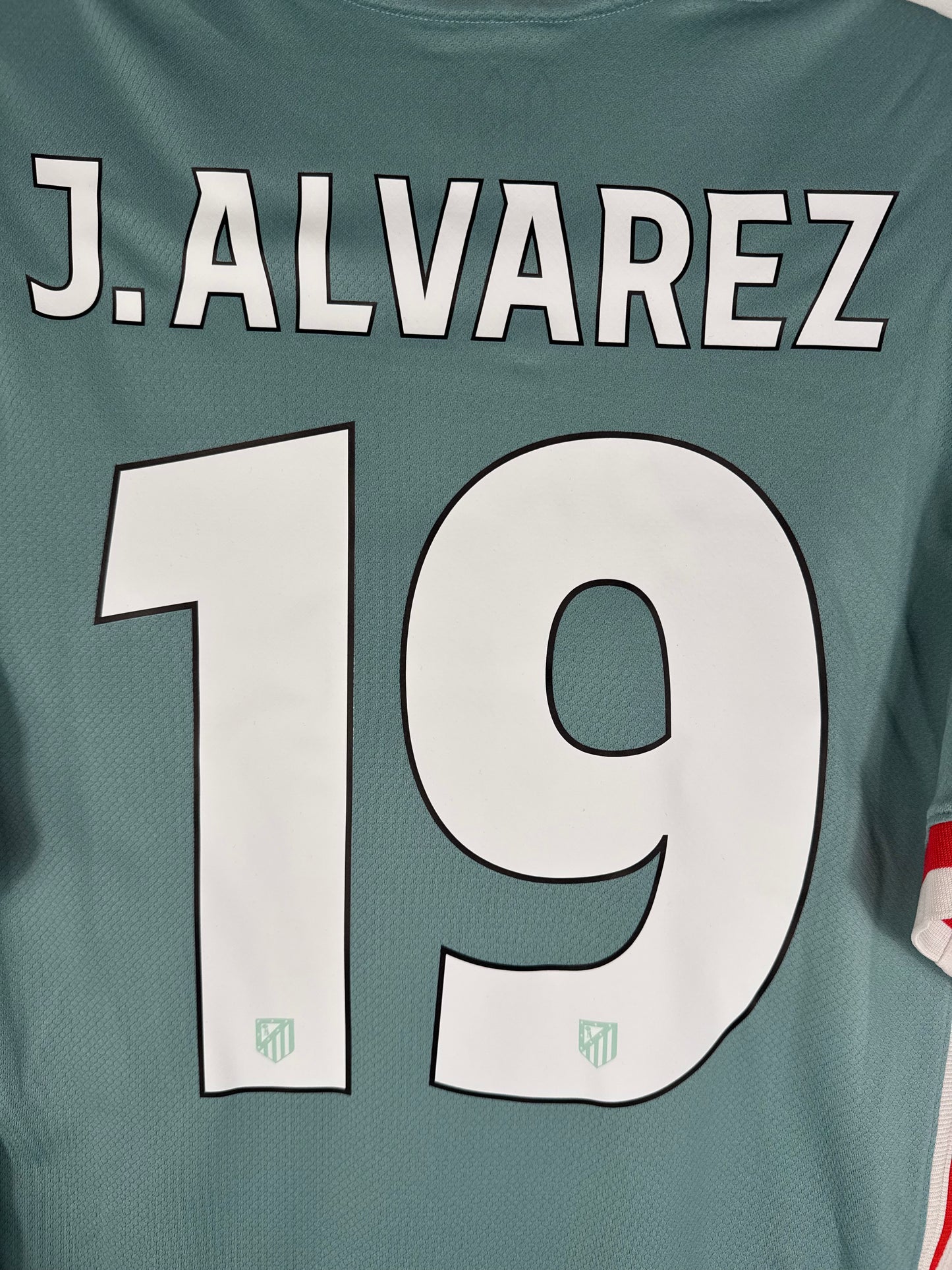 Zoom sur le numéro 19 rouge avec logo de la Liga, police officielle Atletico Madrid 2025.