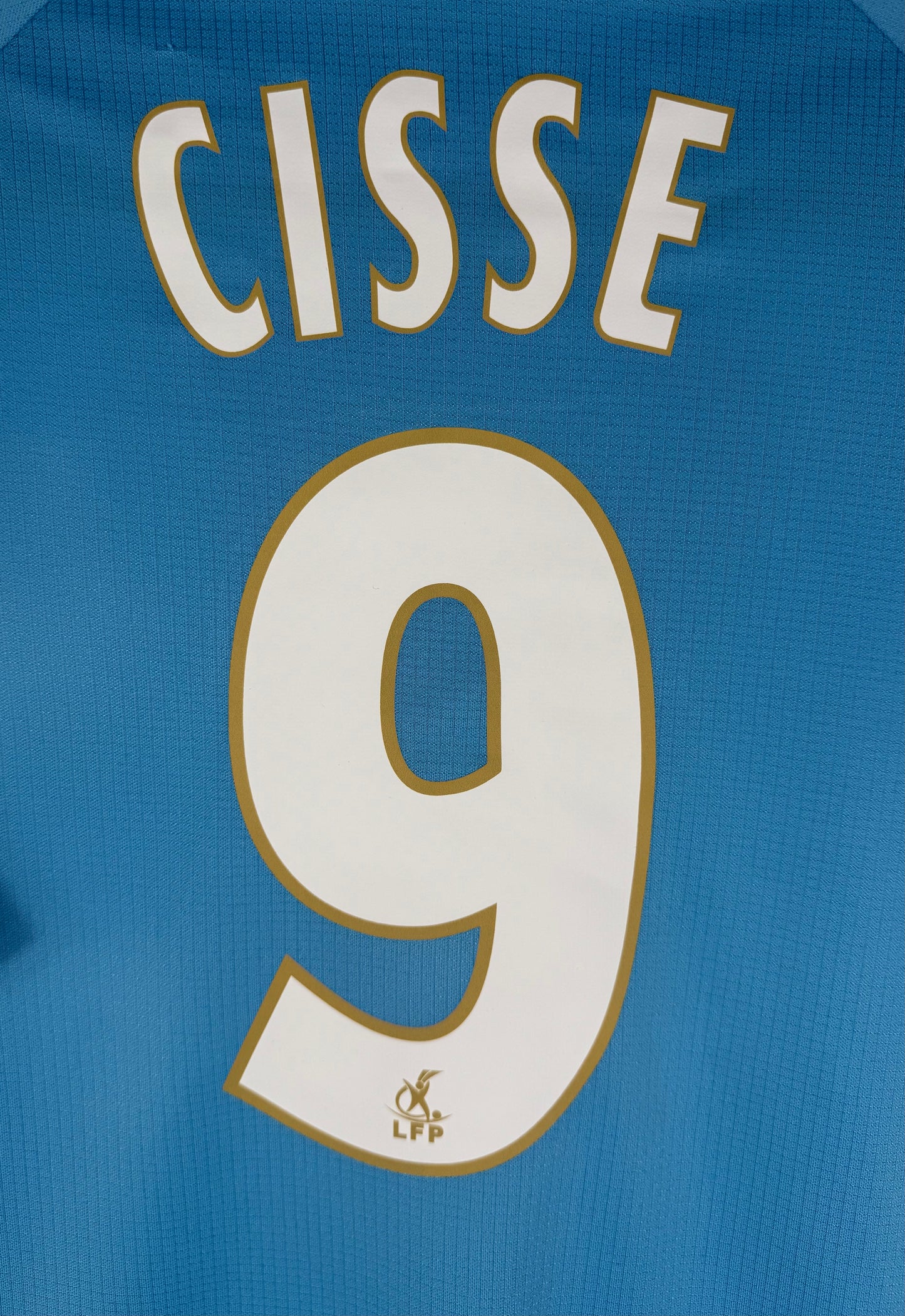 Zoom sur le nom CISSE et le numéro 9 blanc et or au dos du maillot.