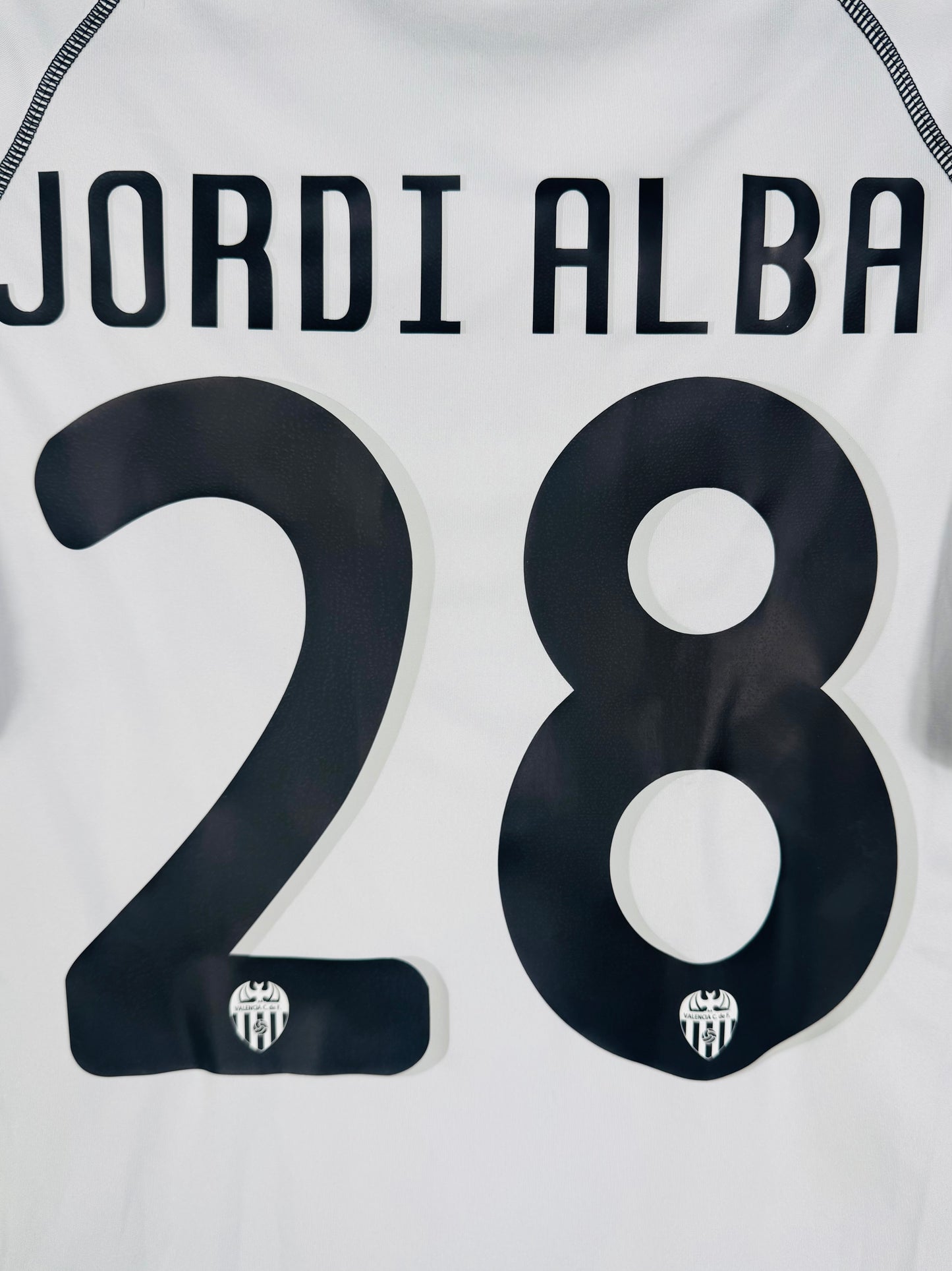 Zoom sur le nom JORDI ALBA et le numéro 28 noir (numéro de jeune joueur).