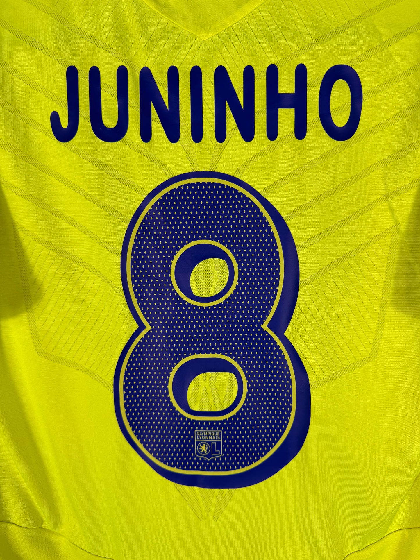 Zoom sur le nom JUNINHO et le numéro 8 bleu marine, typographie officielle utilisée en Ligue des Champions.