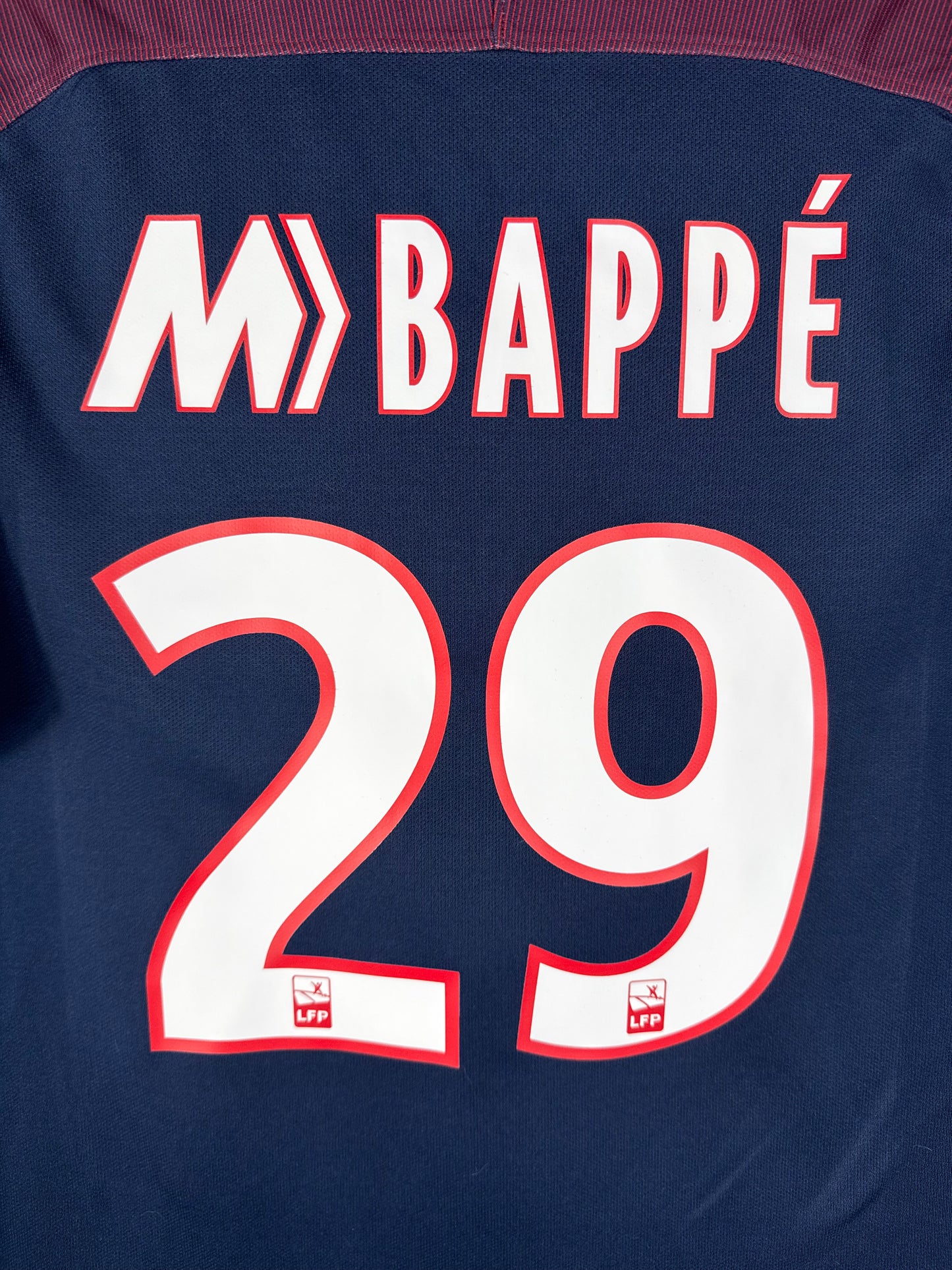 Zoom sur le flocage officiel MBAPPÉ 29 blanc avec liseré sur le maillot domicile parisien.