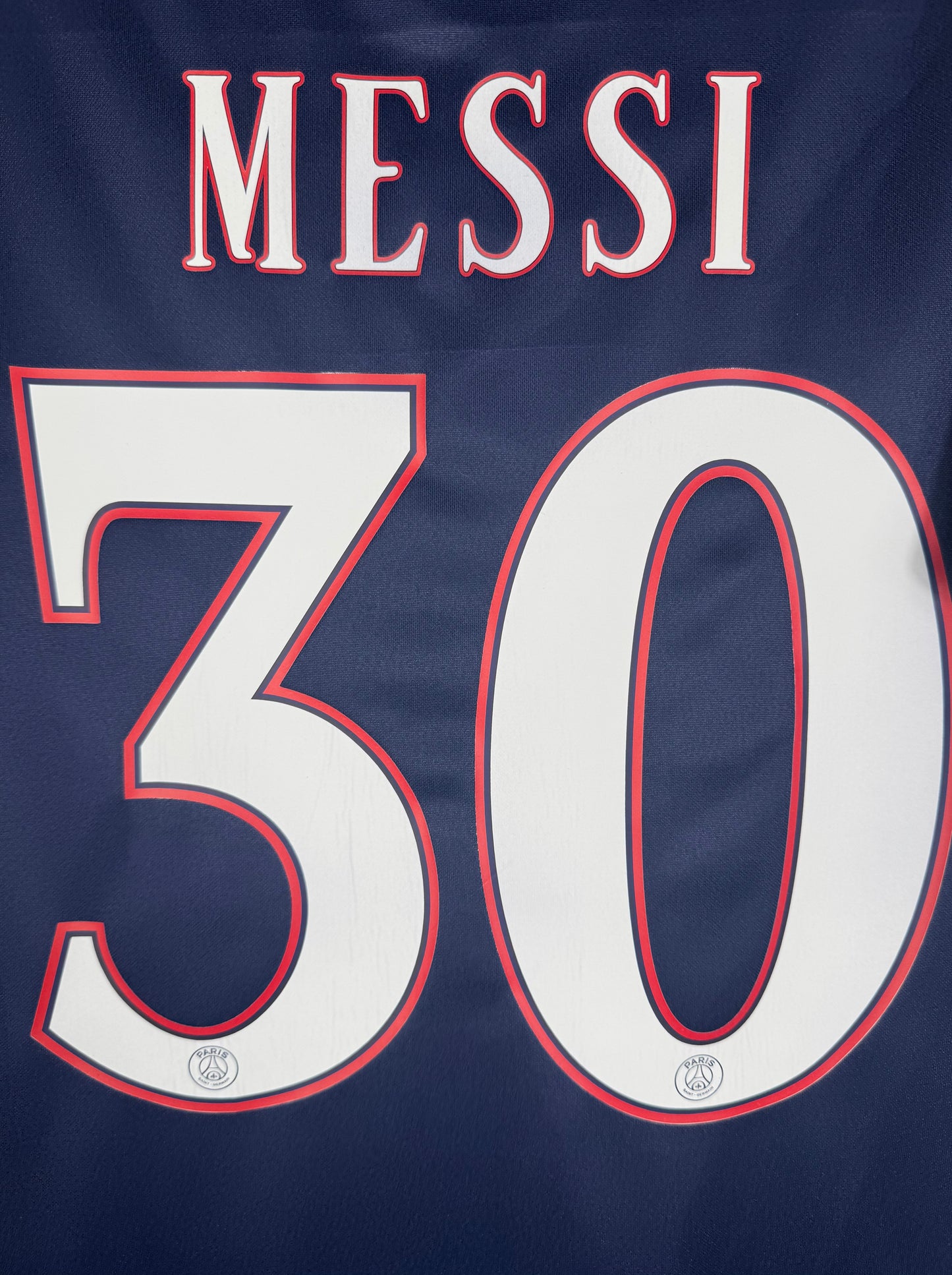 Zoom sur le nom MESSI et le numéro 30 rouge et bleu typographie officielle.