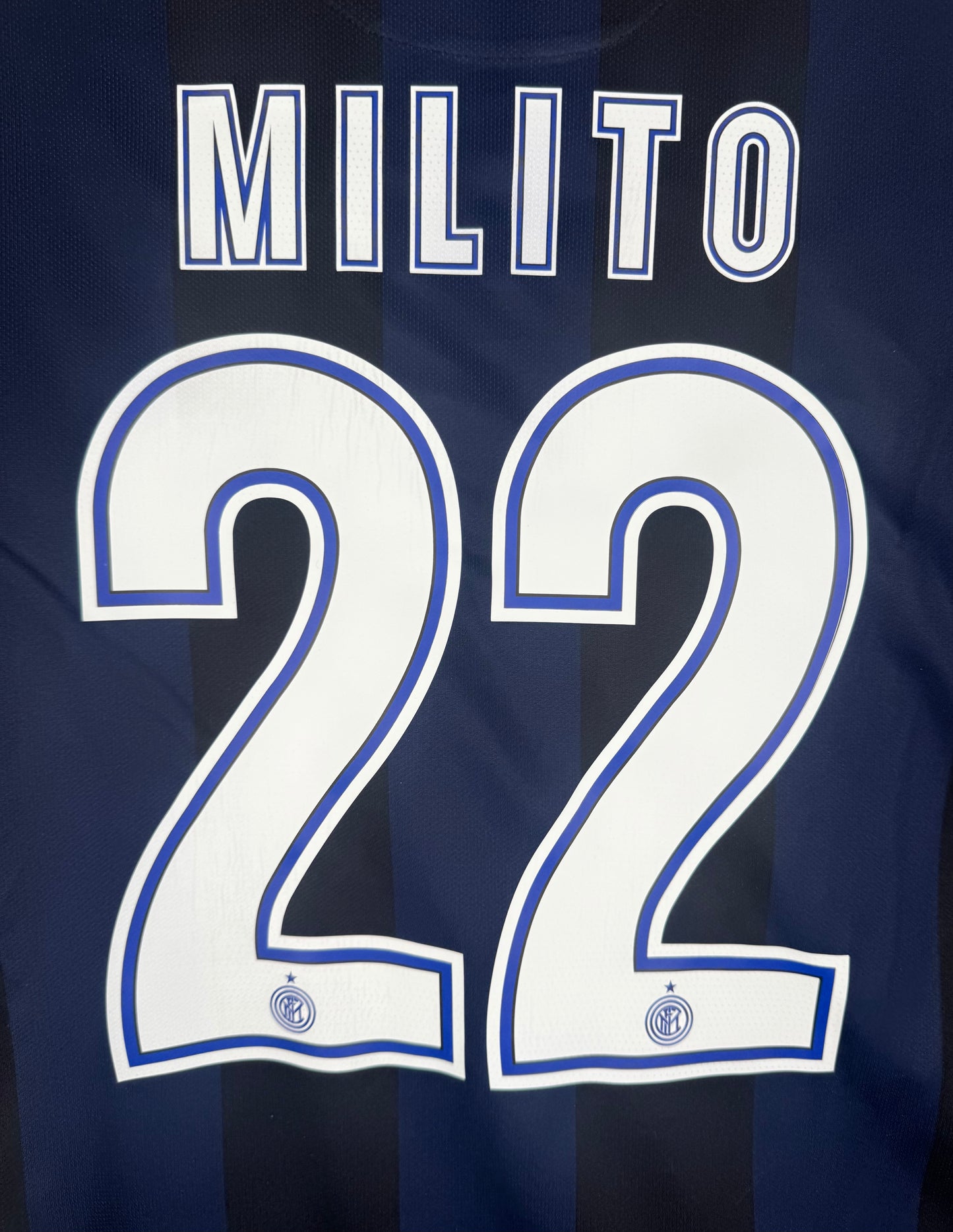 Zoom sur le nom MILITO et le numéro 22 blanc avec le logo du club en bas du chiffre.