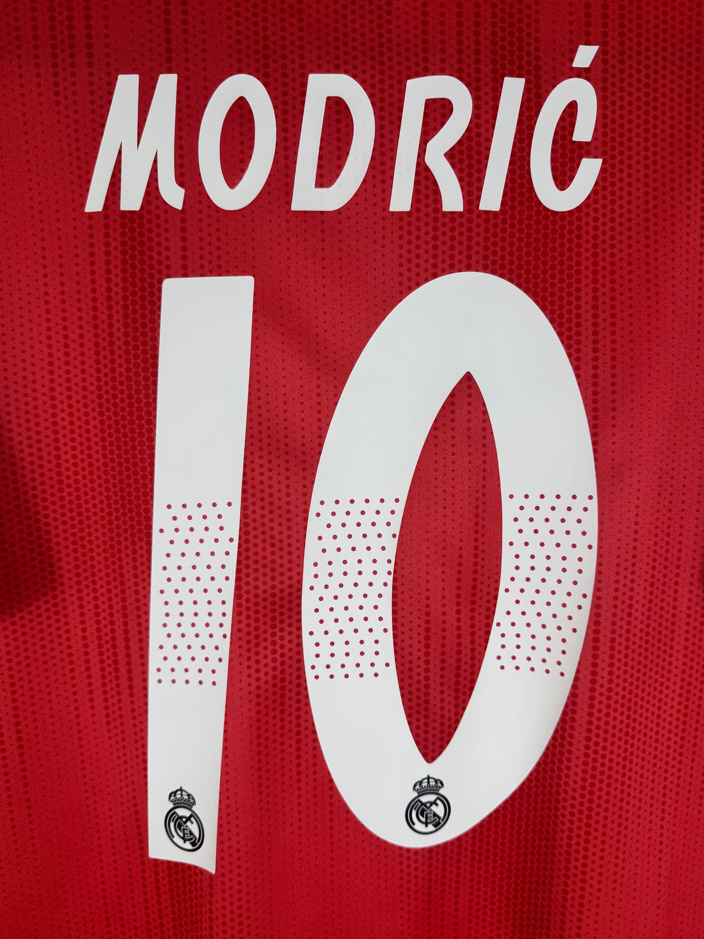 Zoom sur le nom MODRIC et le numéro 10 avec le détail ajouré typique de la saison.