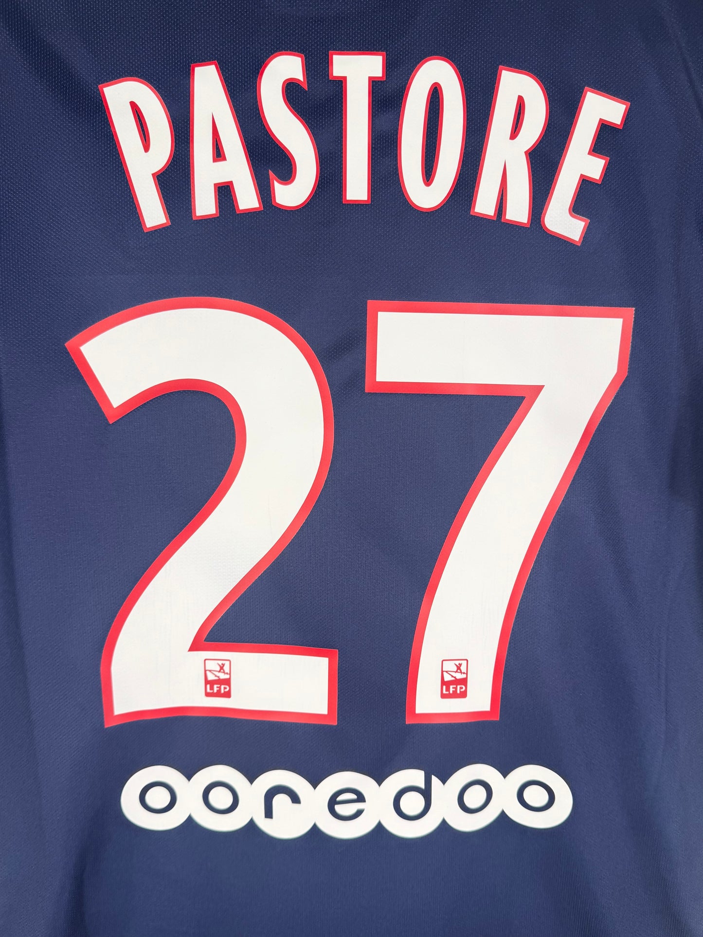 Zoom sur le nom PASTORE et le numéro 27 blanc à contours rouges.