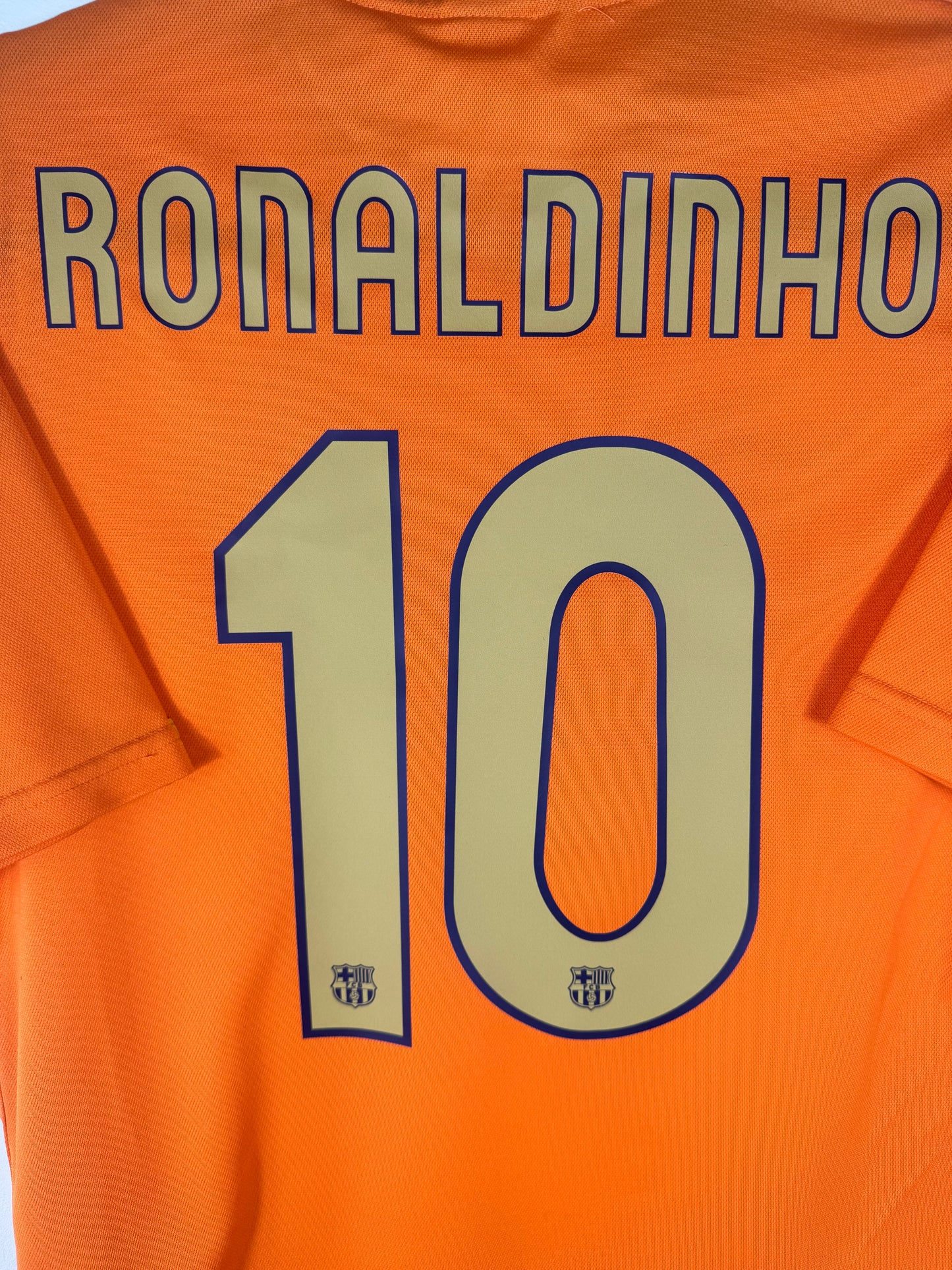 Zoom sur le nom RONALDINHO et le numéro 10 jaune avec logo du club intégré dans la typographie.