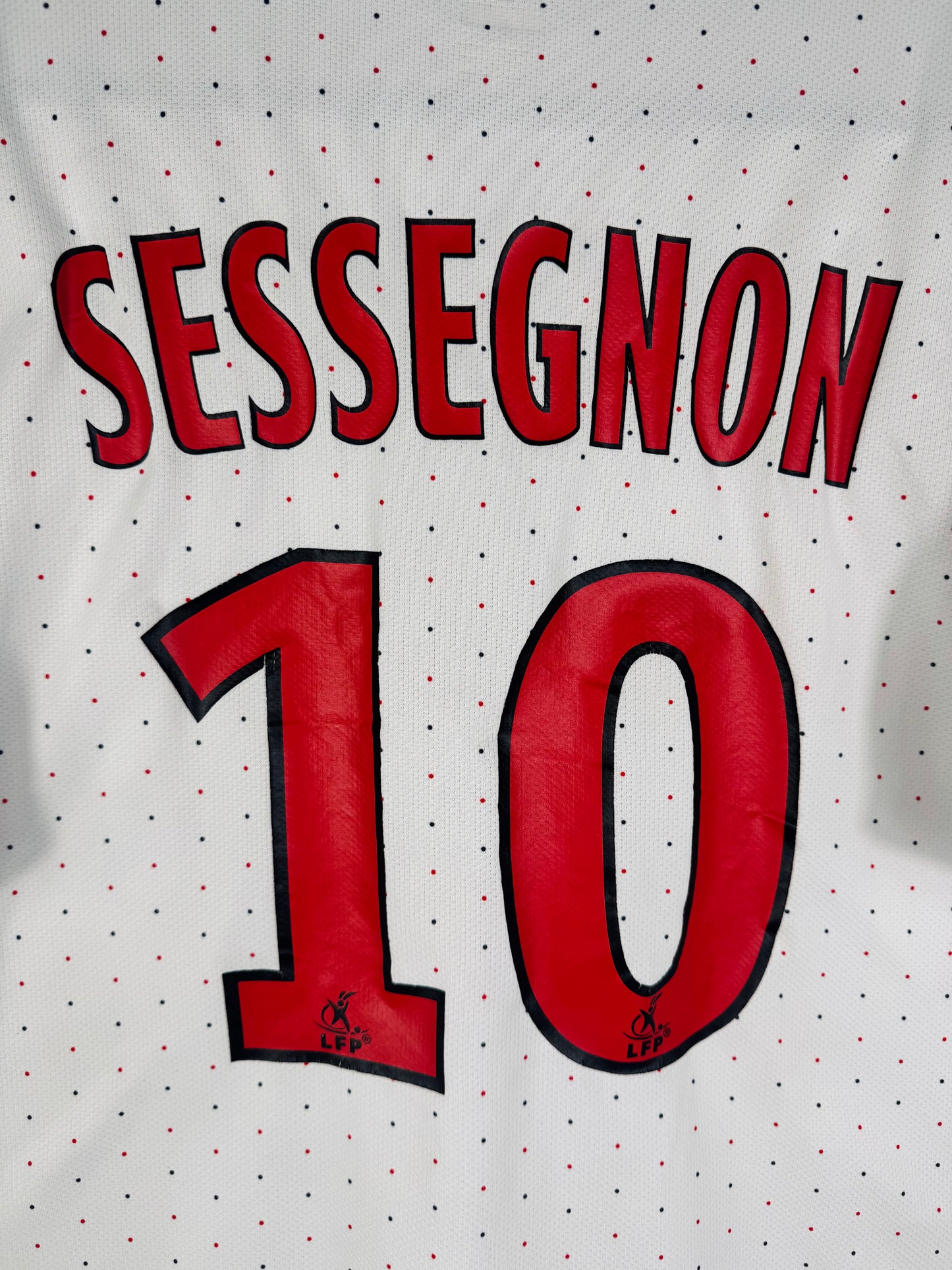 Zoom sur le nom SESSEGNON et le numéro 10 rouge, police officielle de la Ligue 1 2010.