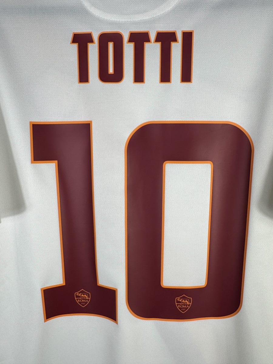 Gros plan du flocage TOTTI 10 bordeaux cerné d'orange avec écussons Roma miniatures