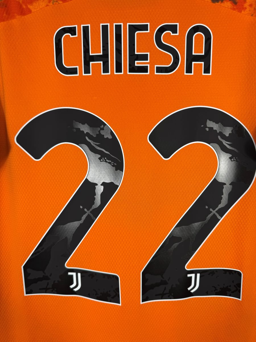 Gros plan du flocage Chiesa N°22 à motif marbré avec écussons Juventus intégrés, maillot third 2020-2021
