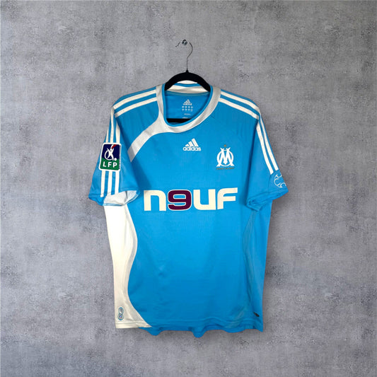Vue de face du maillot OM extérieur 2007 bleu ciel et blanc sponsor Neuf.