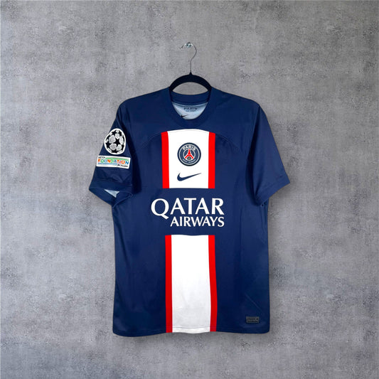 Vue de face du maillot PSG domicile 2023 bleu avec bande Hechter inversée blanche.