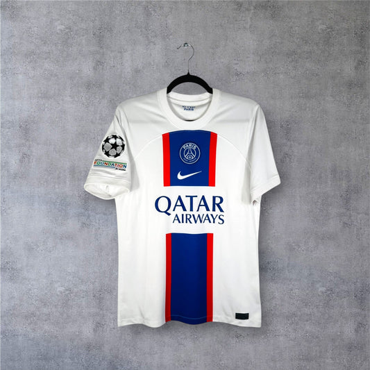Vue de face du maillot PSG 2022/23 Third blanc avec bande verticale Hechter bleue et rouge.