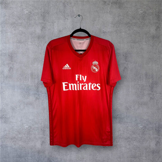 Vue de face du maillot Real Madrid Third 2019 rouge corail porté par le capitaine Ramos.