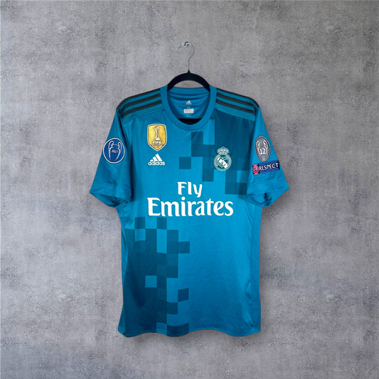 Vue de face du maillot Real Madrid Third 2017/18 couleur sarcelle avec motifs pixelisés.