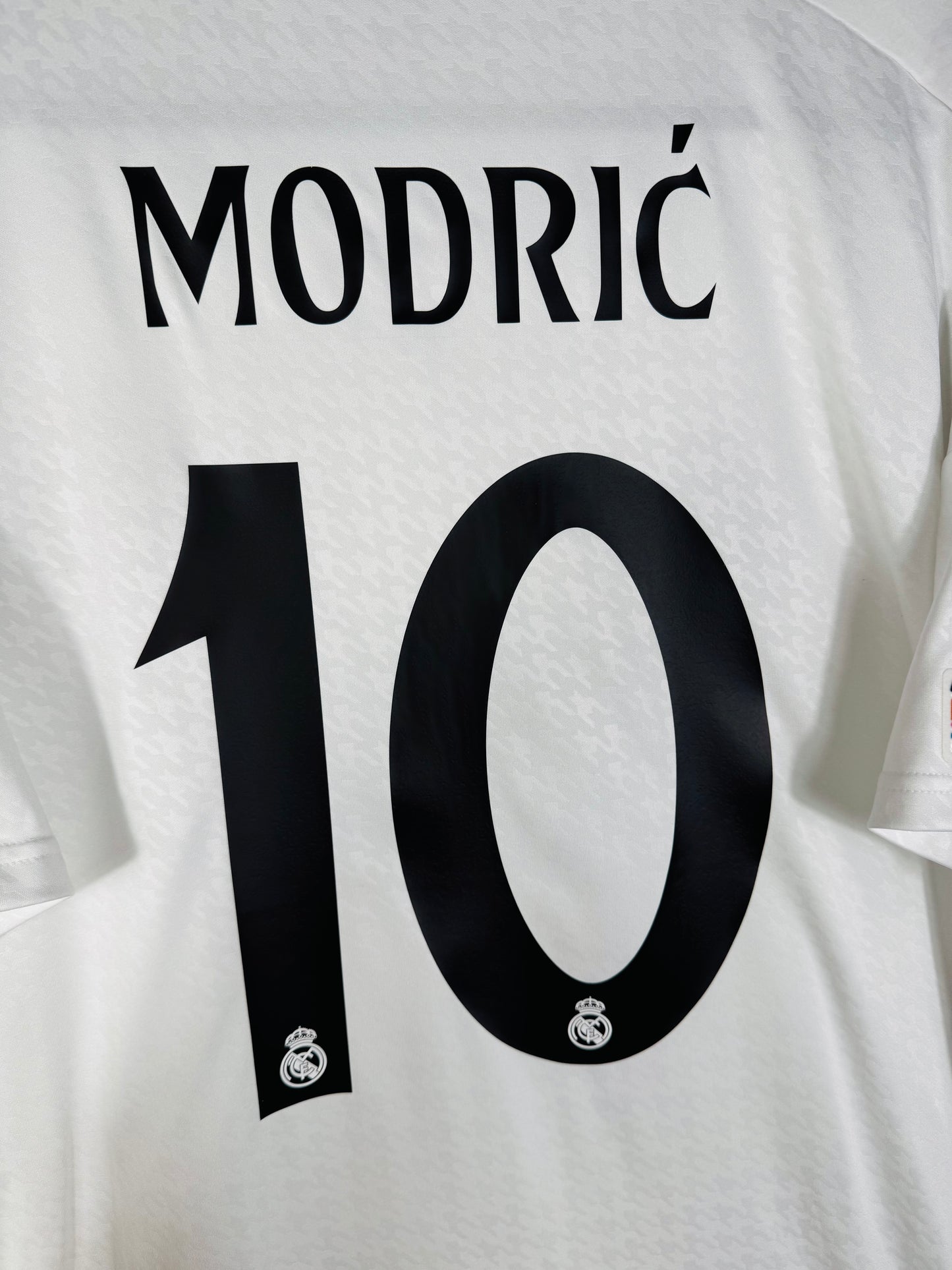 Zoom sur le nom MODRIĆ et le numéro 10 noir avec logo du club, typographie officielle UCL 2024-2025.