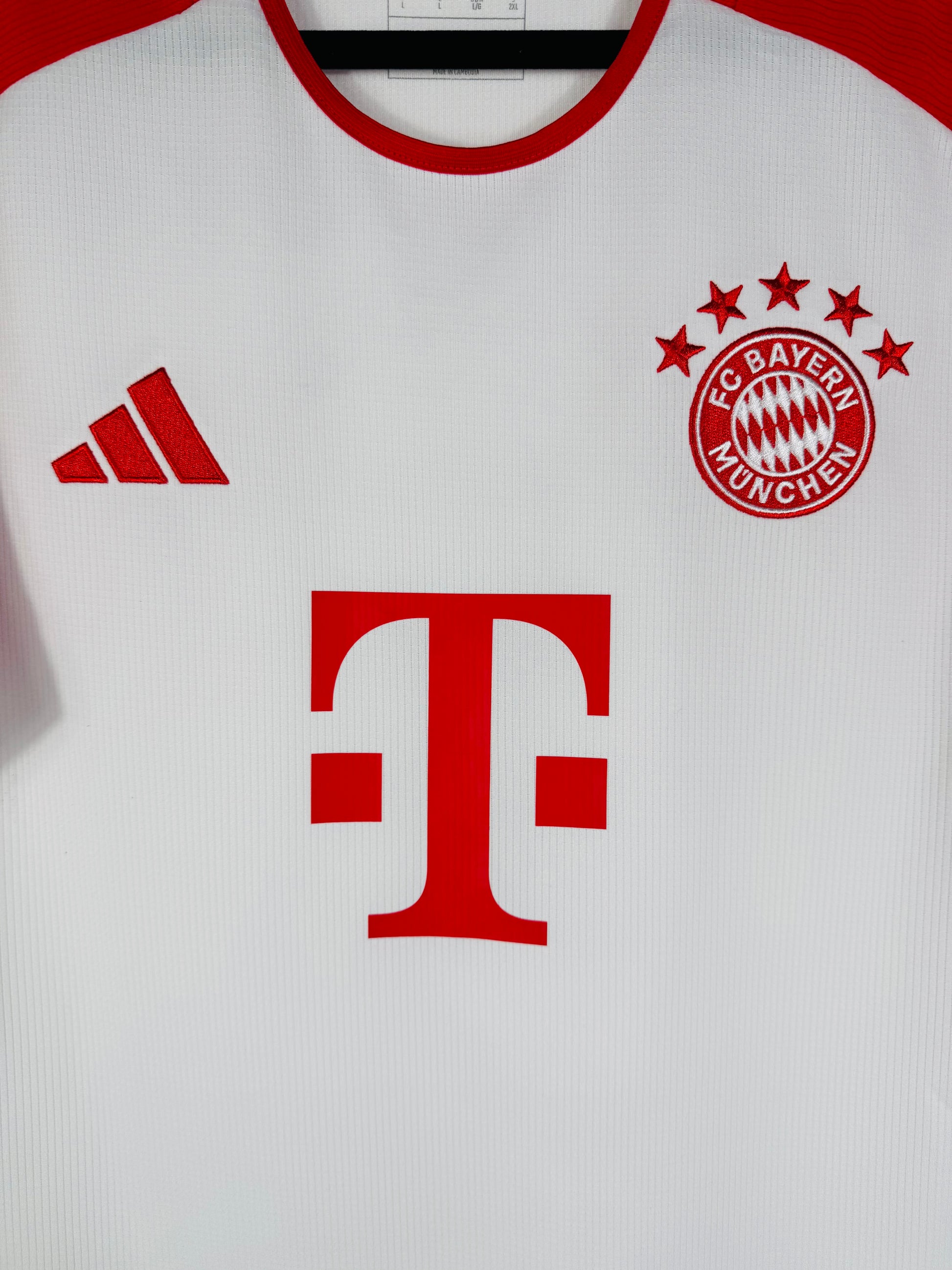 Gros plan sur l'écusson du Bayern Munich aux 5 étoiles et le logo Adidas Performance rouge.