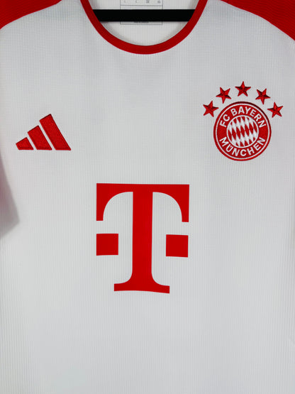 Gros plan sur l'écusson du Bayern Munich aux 5 étoiles et le logo Adidas Performance rouge.
