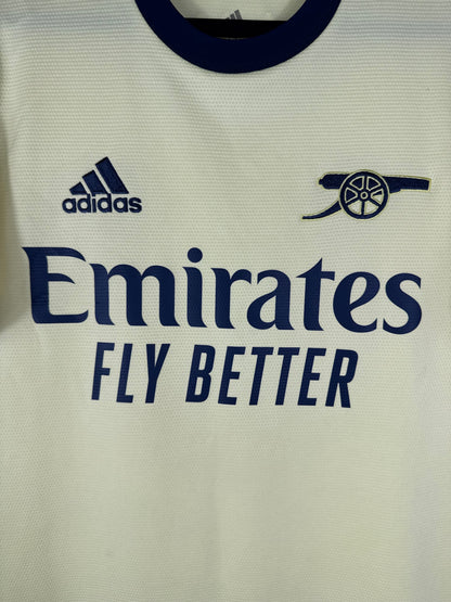 Gros plan sur le logo Canon rétro d'Arsenal et le logo Adidas bleu marine sur le tissu jaune perle.