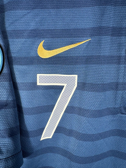 Gros plan sur l'écusson de la Fédération Française de Football et le swoosh Nike brodés en doré.