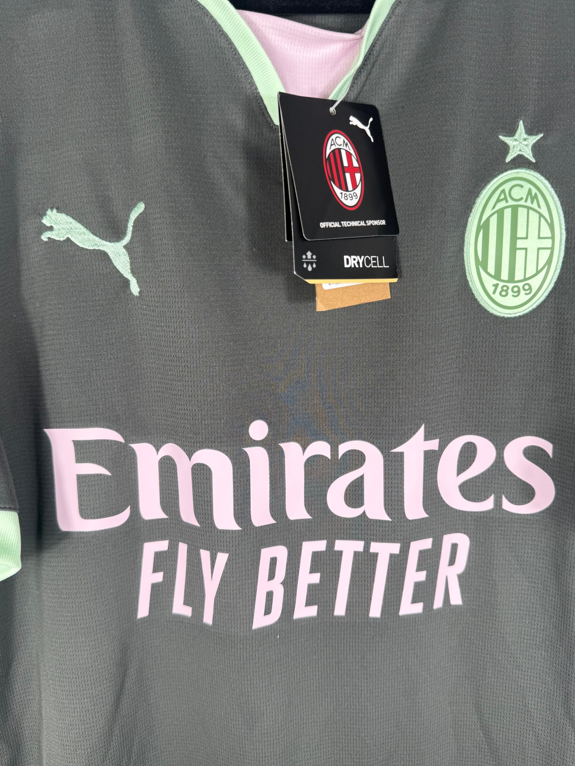 Gros plan sur l'écusson Milan vert menthe et le sponsor Emirates rose.