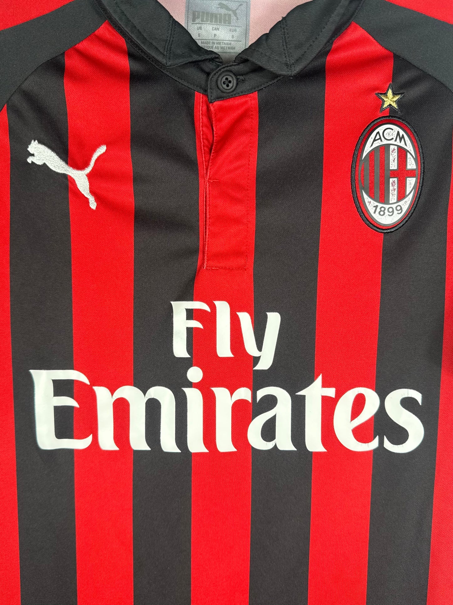 Gros plan sur l'écusson de l'AC Milan et le sponsor Fly Emirates sur les rayures.