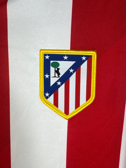 Gros plan sur l'écusson de l'Atlético Madrid brodé sur les rayures rouges et blanches.