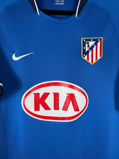 Gros plan sur l'écusson de l'Atletico Madrid et le sponsor KIA sur le maillot extérieur bleu.