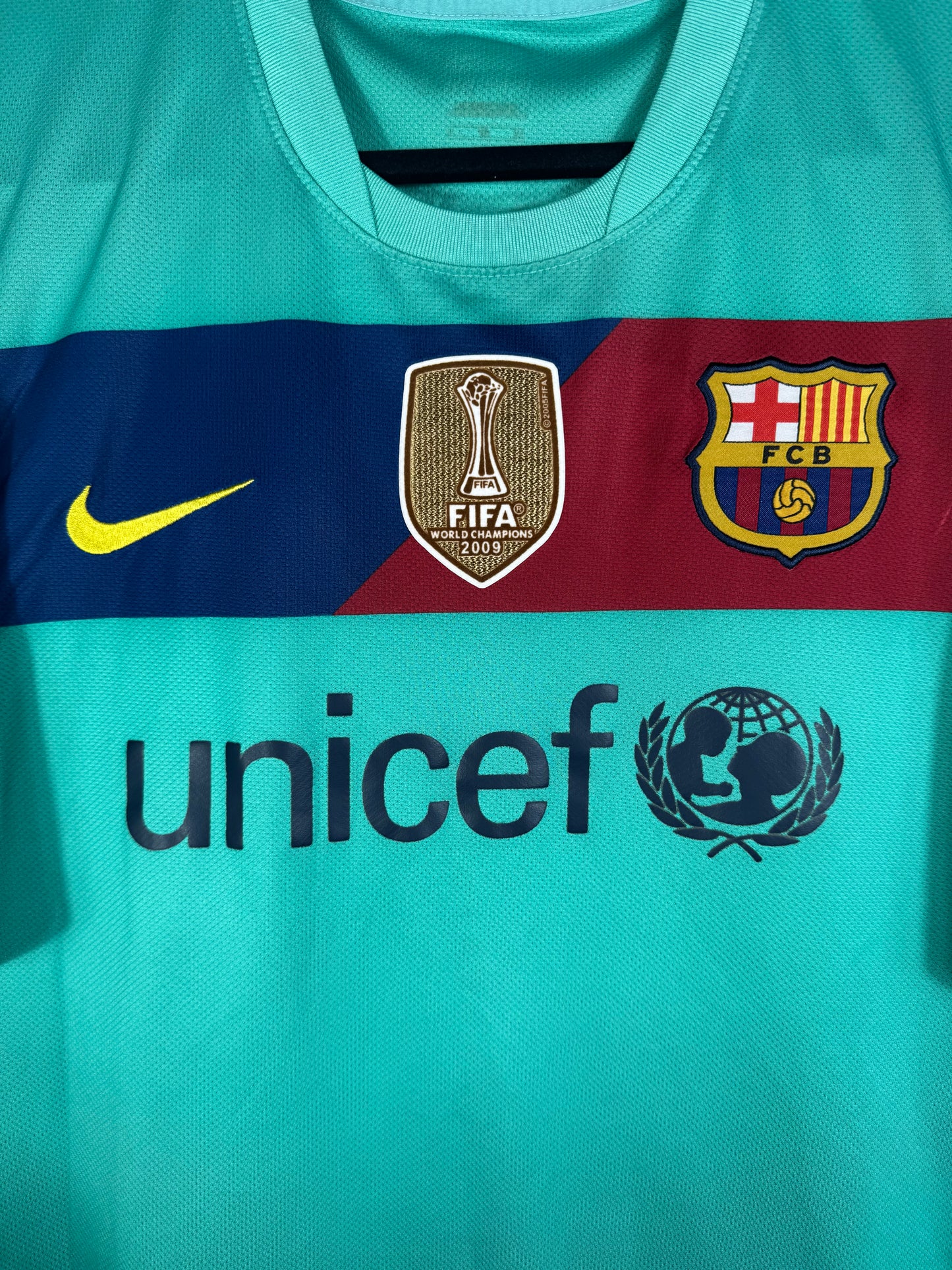 Gros plan sur l'écusson du Barça, le logo Nike jaune et le badge doré FIFA Club World Cup sur la bande pectorale.