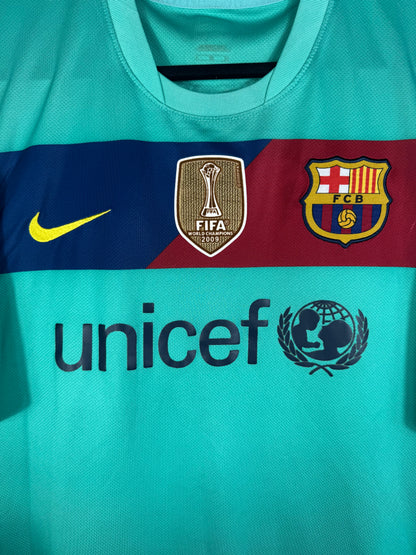 Gros plan sur l'écusson du Barça, le logo Nike jaune et le badge doré FIFA Club World Cup sur la bande pectorale.