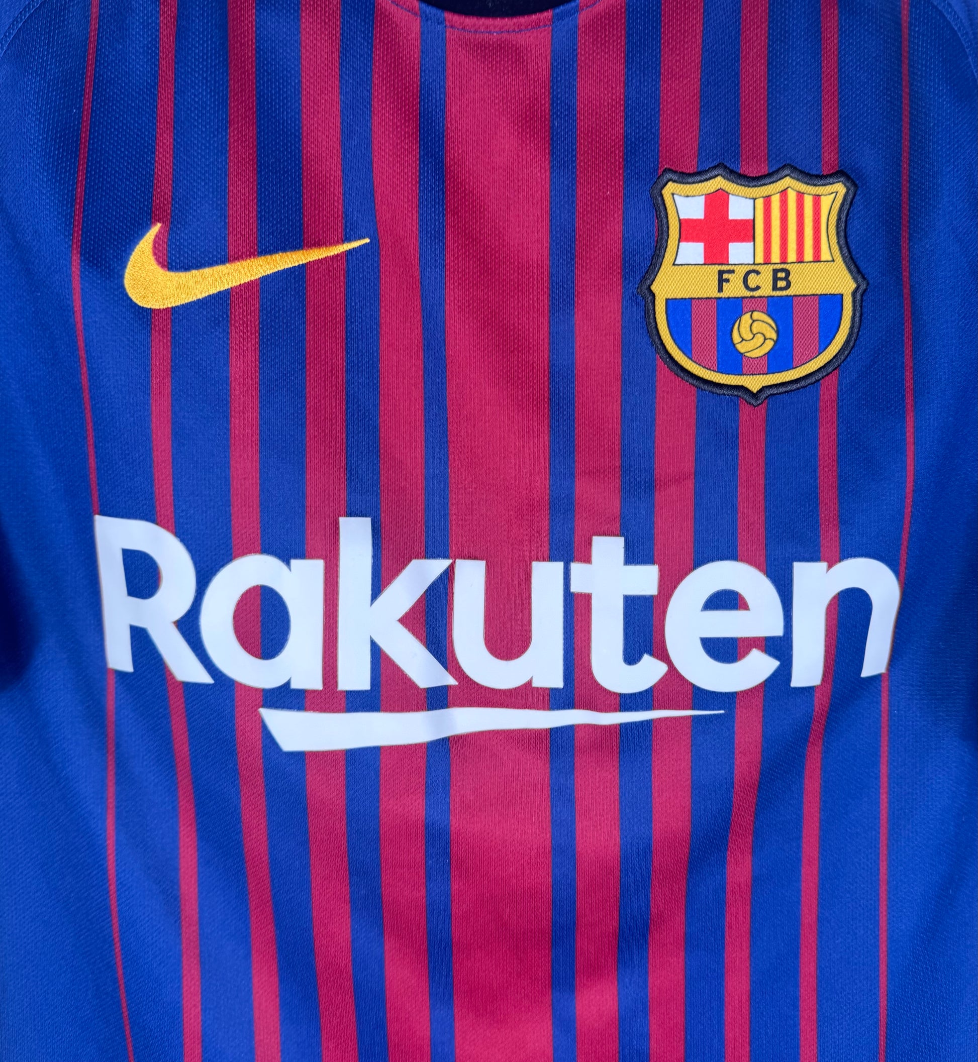 Gros plan sur l'écusson brodé FCB et le logo Nike jaune sur les rayures blaugrana.