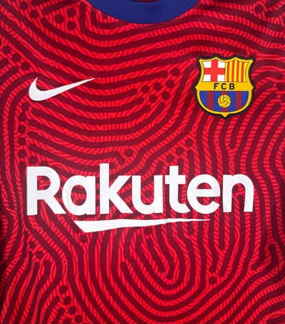 Gros plan sur l'écusson FC Barcelone et logo Nike sur motif abstrait rouge.