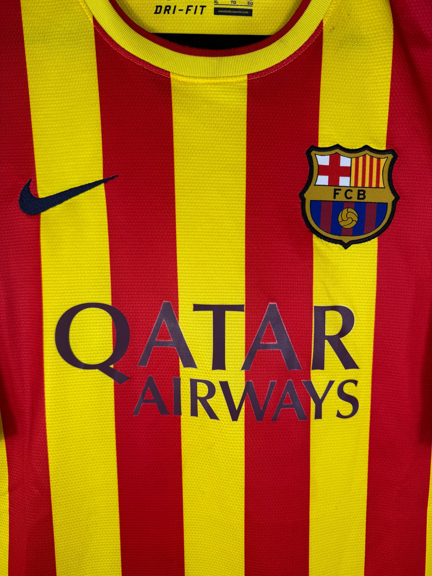 Gros plan sur l'écusson du FC Barcelone, le logo Nike marine et le sponsor sur le tissu jaune et rouge.