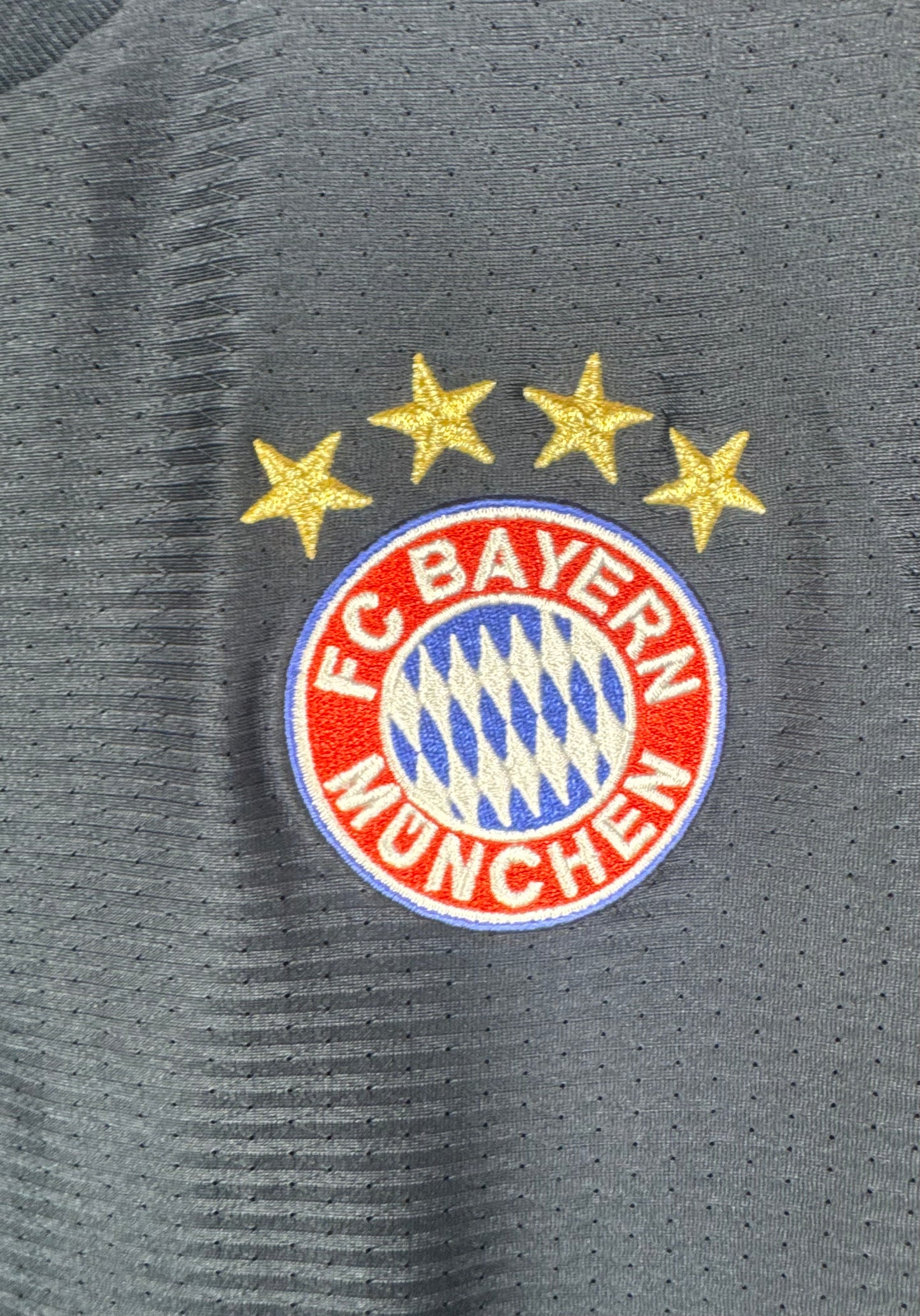 Gros plan sur l'écusson 4 étoiles du Bayern et la texture aérée du maillot Adidas.