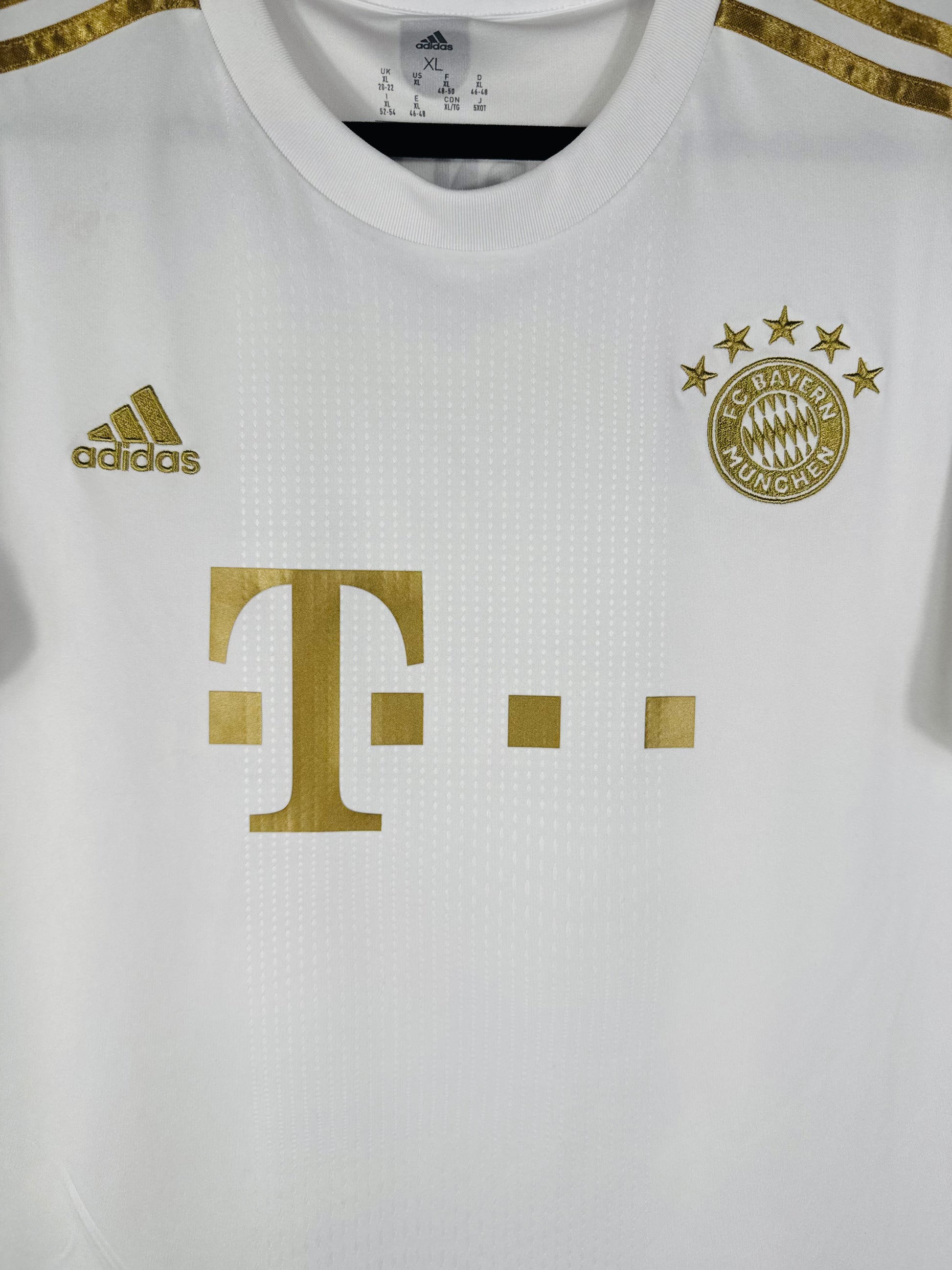 Gros plan sur l'écusson du Bayern Munich aux 5 étoiles et le logo Adidas brodés en or métallique.