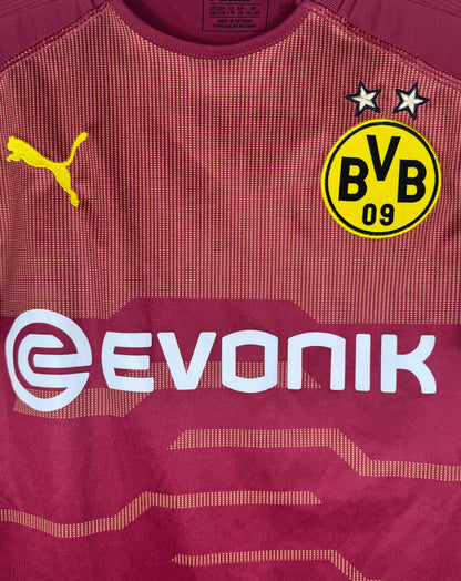 Gros plan sur l'écusson BVB 09 et le sponsor Evonik blanc sur fond rouge texturé.