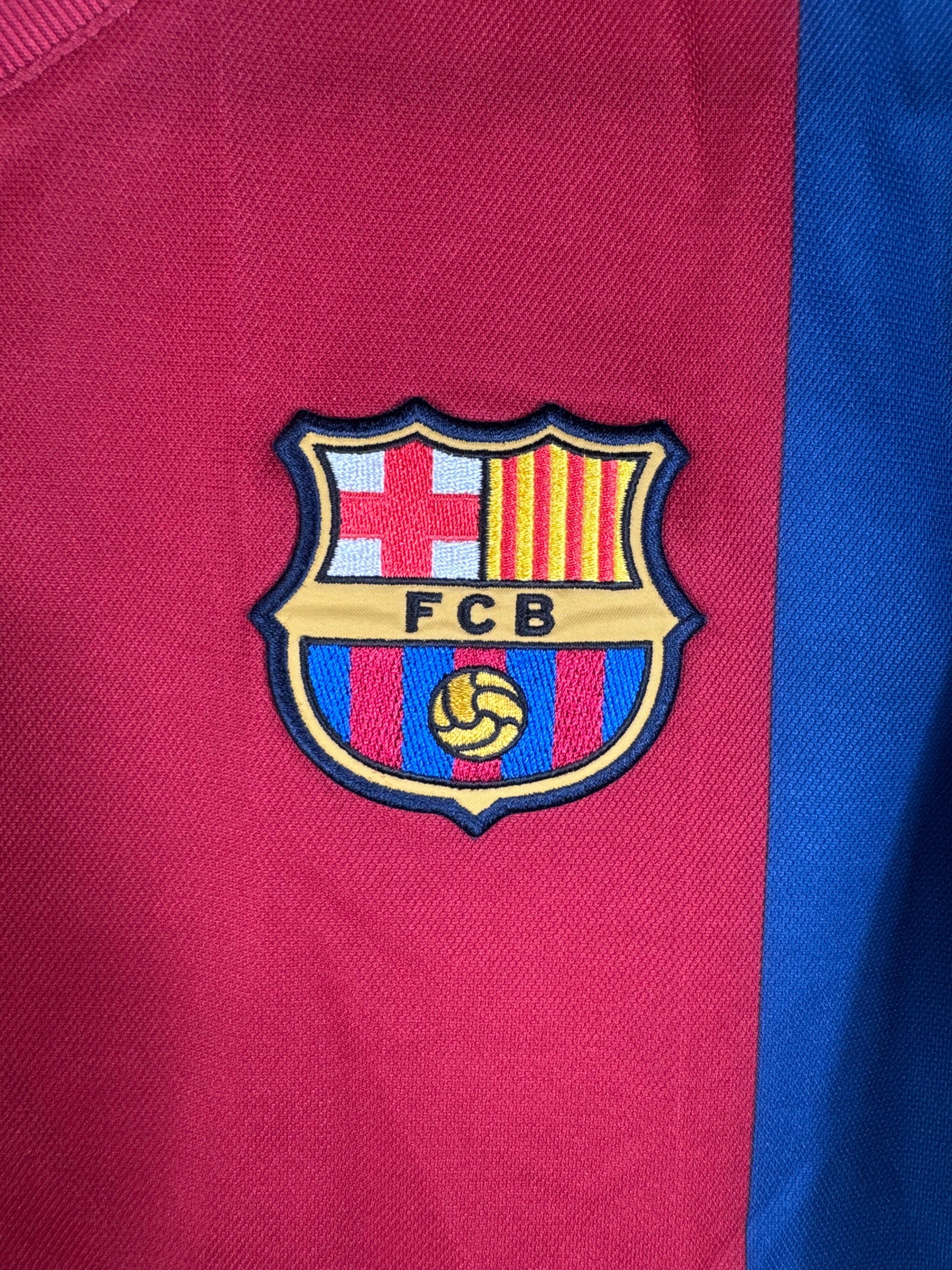 Gros plan sur l'écusson historique du FC Barcelone brodé sur le tissu domicile.