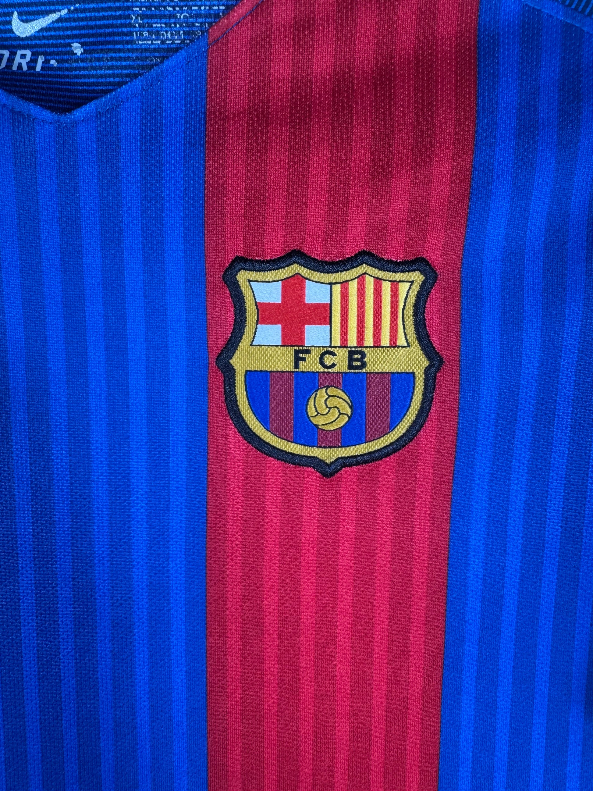 Gros plan sur l'écusson du FC Barcelone brodé et le logo Nike doré sur le torse.