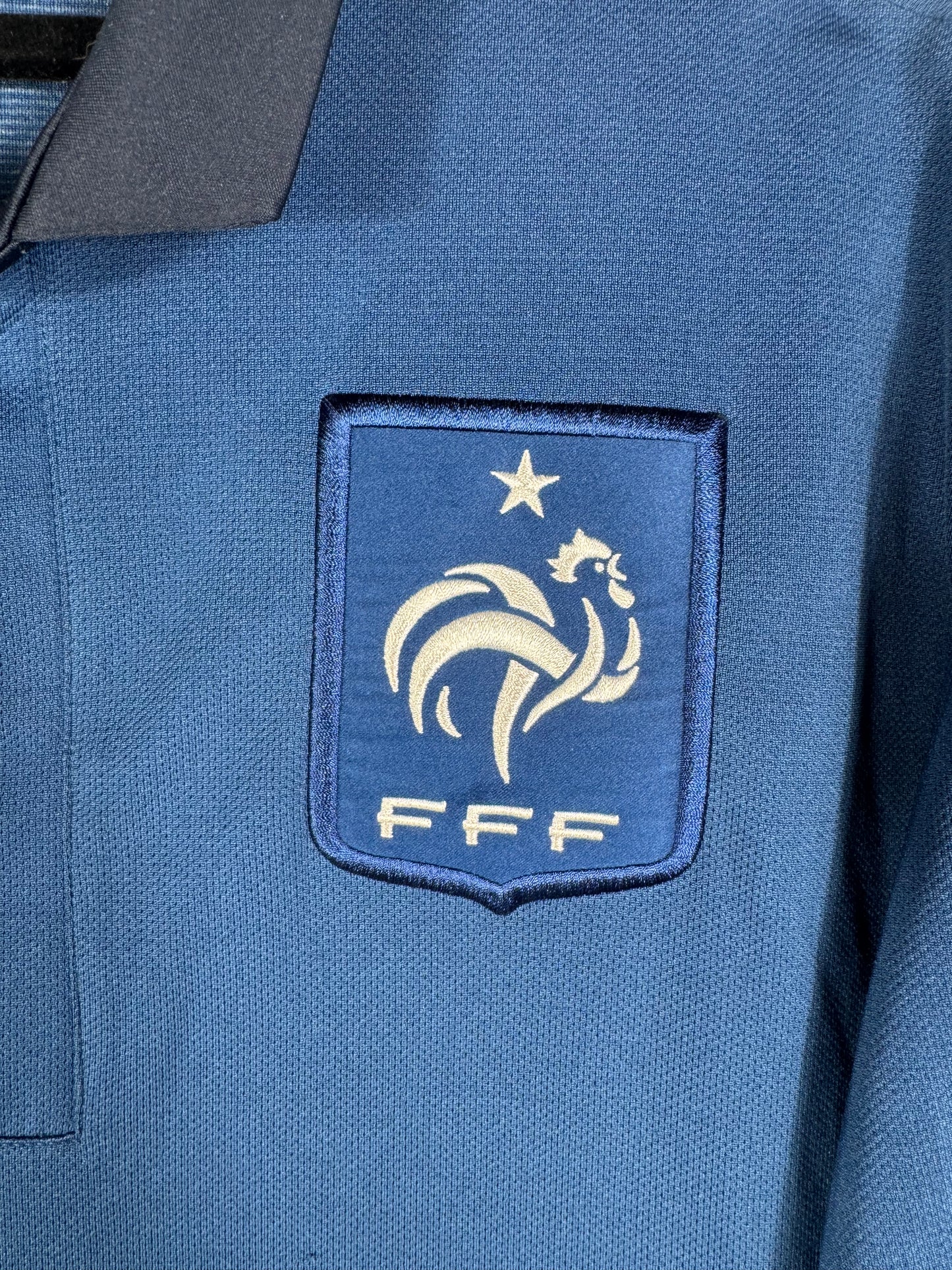 Gros plan sur le blason brodé de la FFF et le logo Nike blanc sur le torse du maillot.