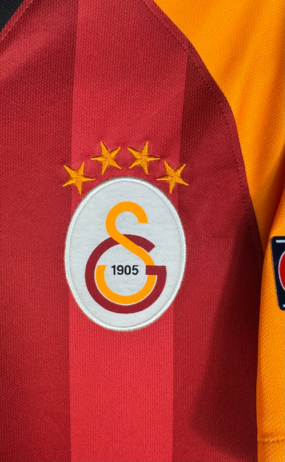 Gros plan sur l'écusson 4 étoiles de Galatasaray sur fond rouge et orange.