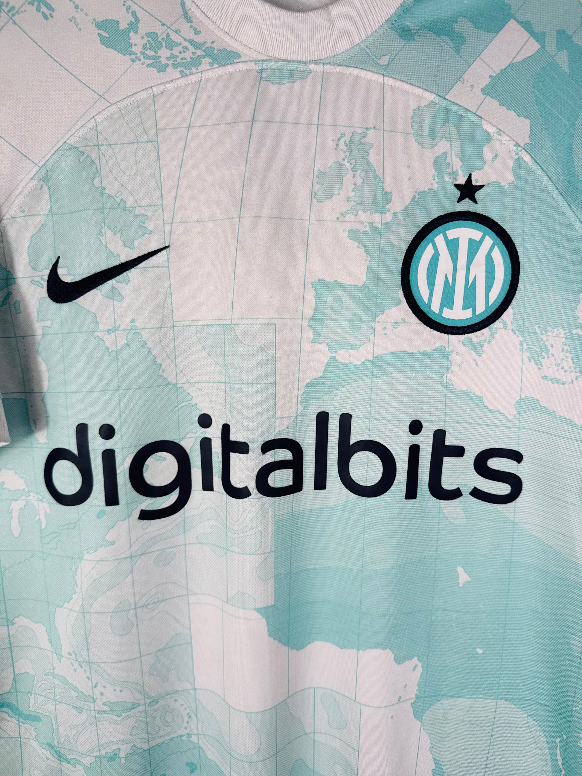 Gros plan sur l'écusson de l'Inter Milan monochrome et le logo Nike bleu cyan sur le motif carte du monde.