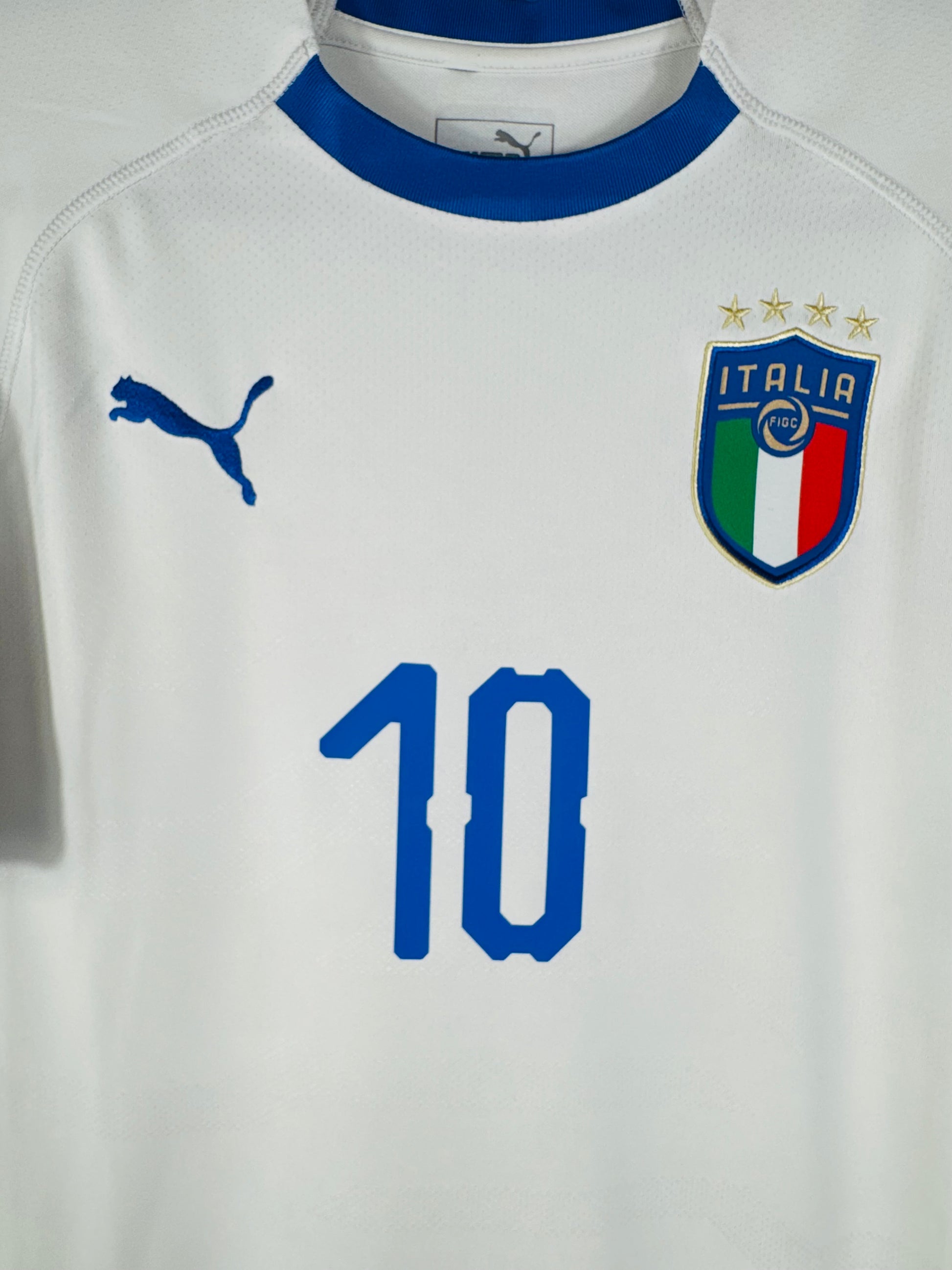 Gros plan sur l'écusson de la Fédération Italienne de Football et le logo Puma bleu sur fond blanc.