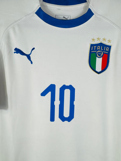 Gros plan sur l'écusson de la Fédération Italienne de Football et le logo Puma bleu sur fond blanc.