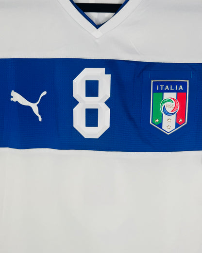 Gros plan sur l'écusson FIGC Italie et le numéro 8 centrés sur la bande bleue du maillot.
