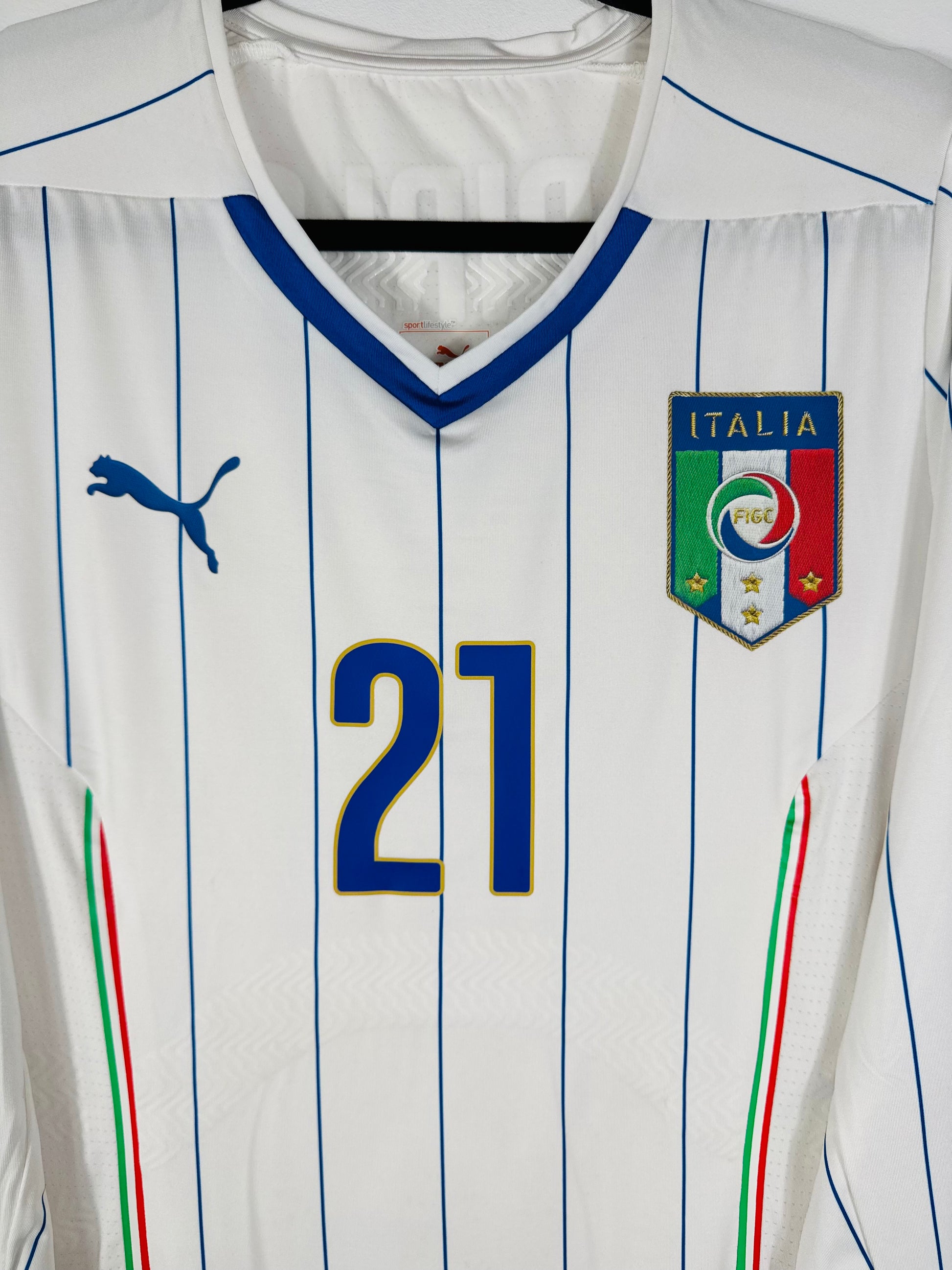 Gros plan sur l'écusson de l'Italie et le logo Puma bleus thermocollés sur la poitrine blanche.