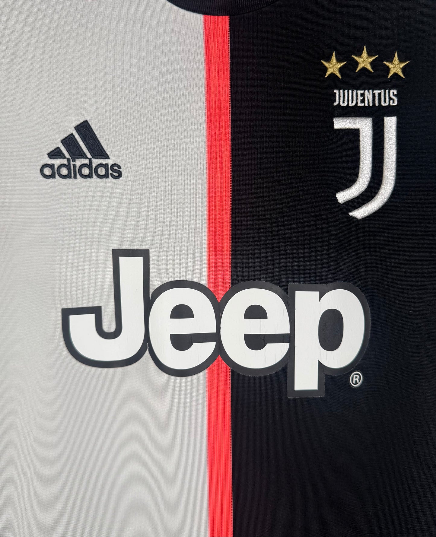 Gros plan sur le logo J de la Juventus et le sponsor Jeep sur le design bicolore.