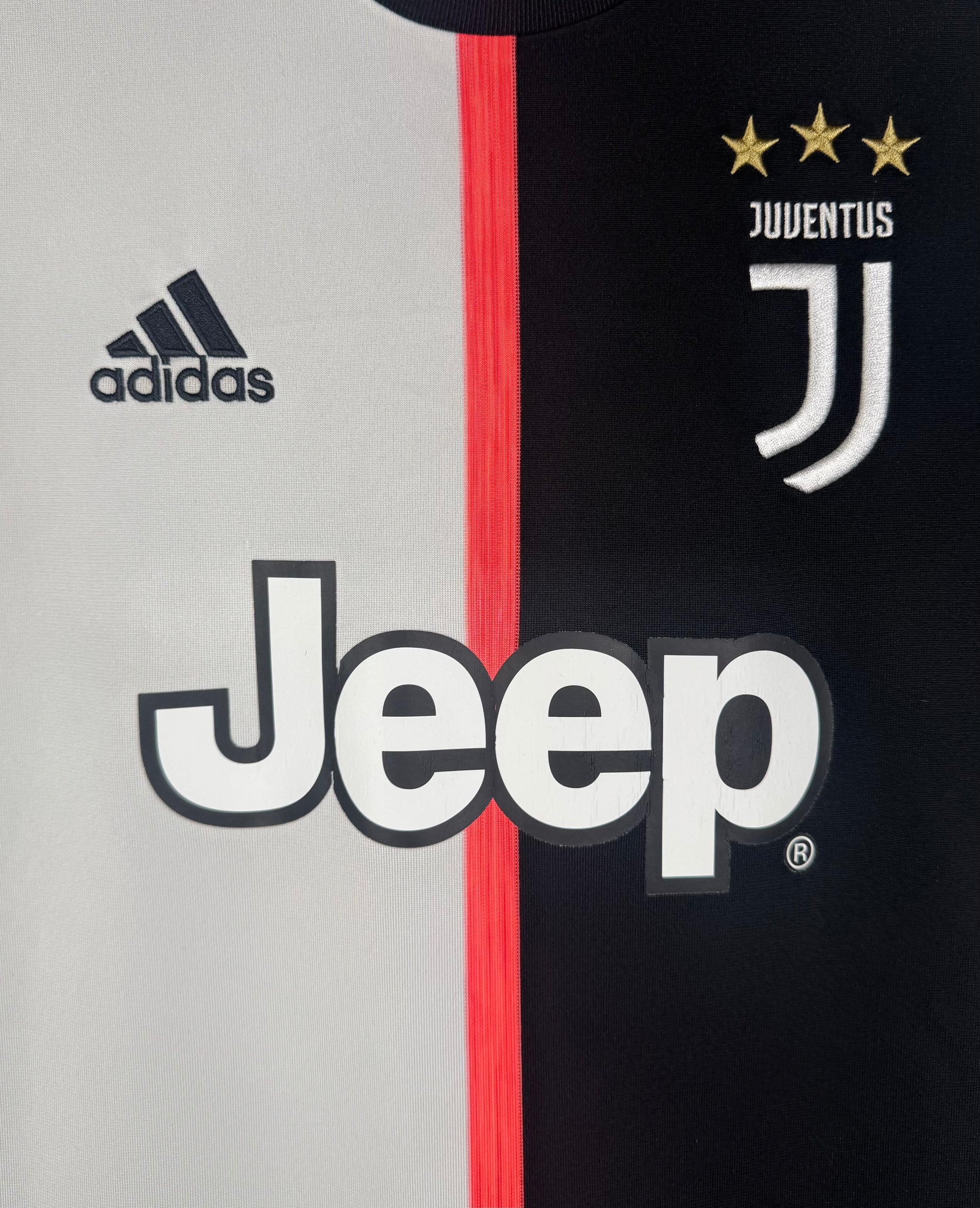 Gros plan sur le logo J de la Juventus et le sponsor Jeep sur le design bicolore.