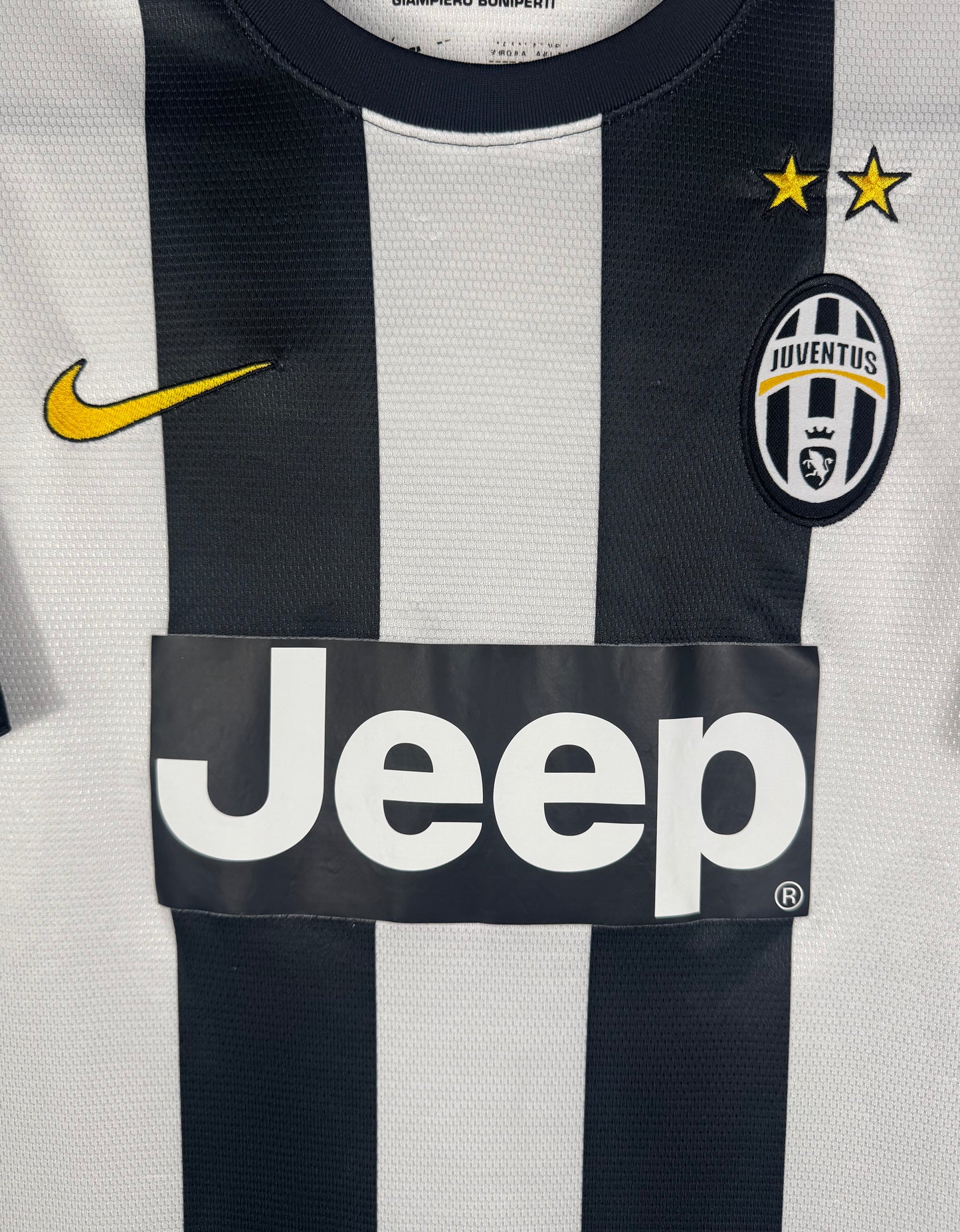 Gros plan sur l'écusson de la Juve avec les 3 étoiles et le swoosh Nike jaune.
