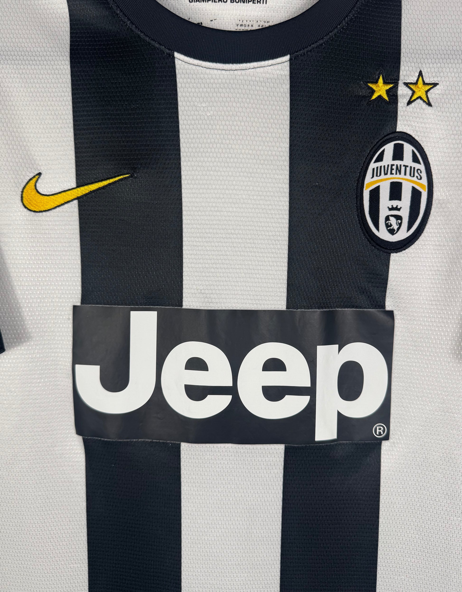 Gros plan sur l'écusson de la Juve avec les 3 étoiles et le swoosh Nike jaune.