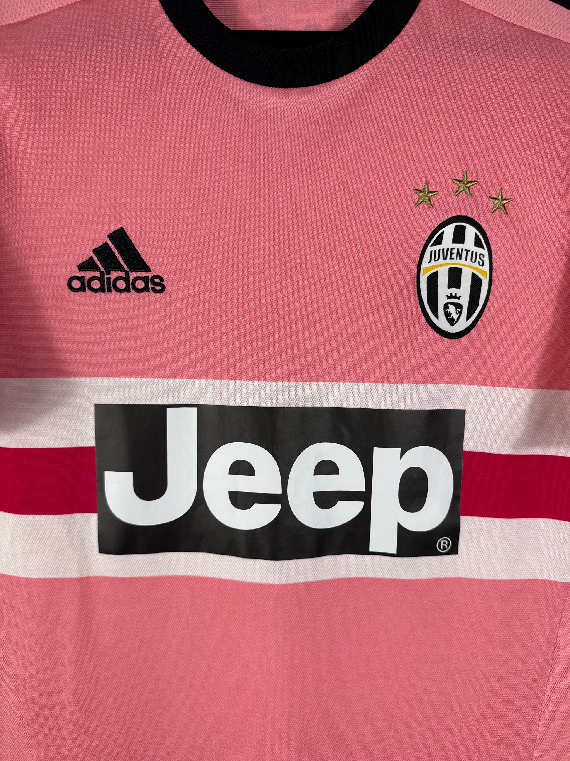 Gros plan sur l'écusson de la Juventus avec ses 3 étoiles d'or et le logo Adidas noir sur le maillot rose.