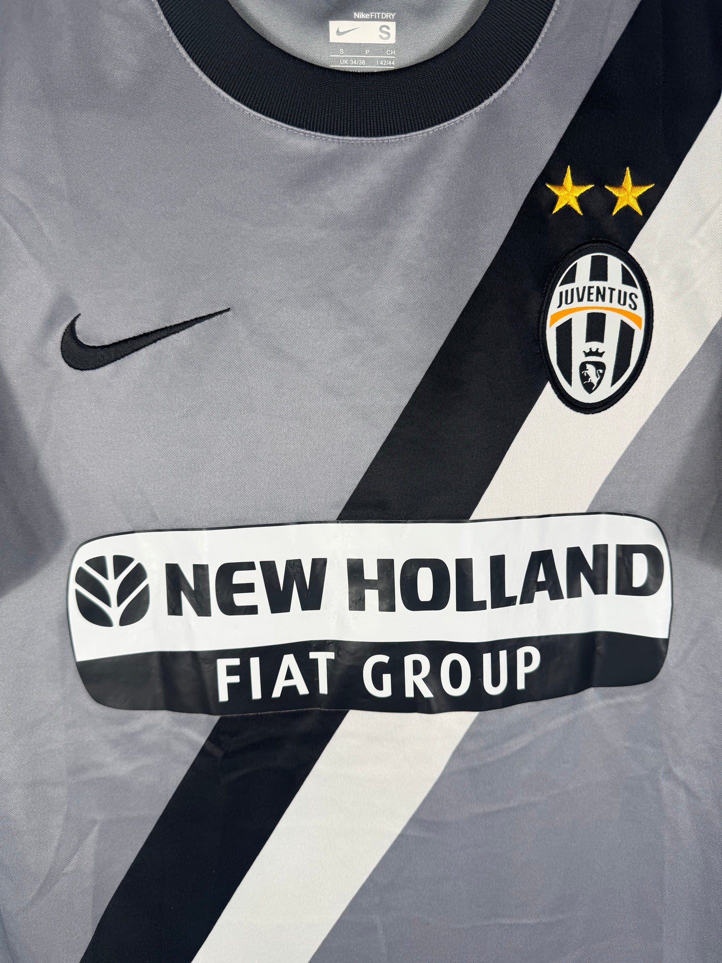Gros plan sur l'écusson Juventus, le swoosh Nike et la bande diagonale noire et blanche.